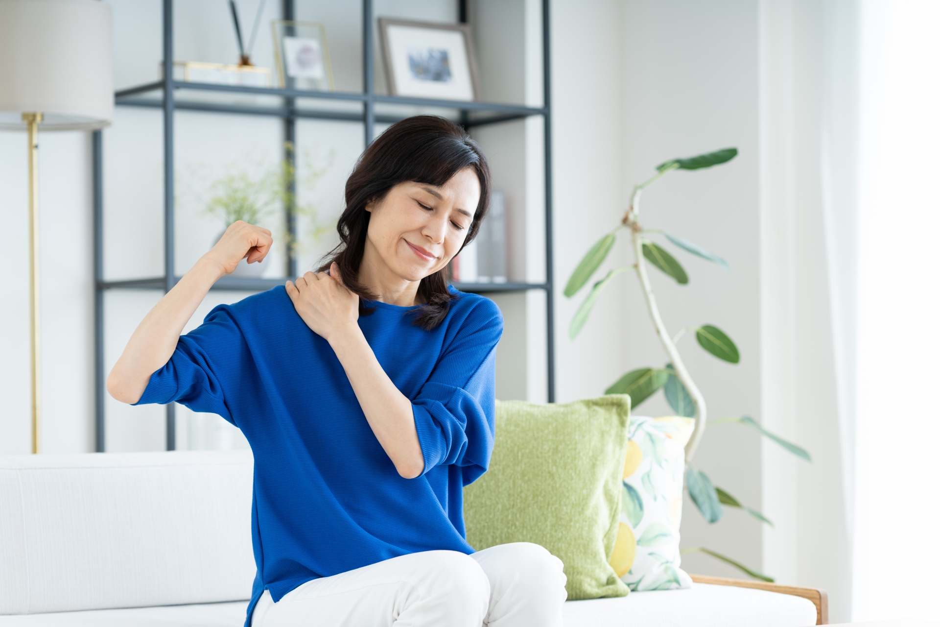 椅子に座って肩まわりのセルフケアをする50代女性
